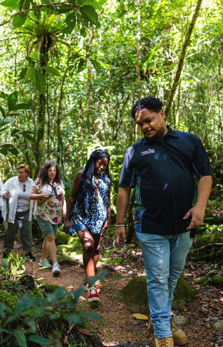 在热带北昆士兰地区的莫斯曼峡谷文化中心，一位原住民向导正带领一群具有多元背景的游客，沿着蜿蜒穿过茂密古老雨林的泥土步道前行，斑驳阳光透过树冠洒落林间。© 澳大利亚旅游局版权所有
