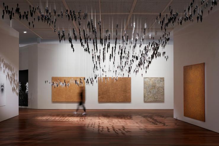 伊里巴娜画廊展览景象，展出作品（从左到右）分别是 Yukultji Napangati 的《无题》（2005 年）、Doreen Reid Nakamarra 的《无题》（2007 年）、Bobby West Tjupurrula 的《Tingari sites around Kiwirrkura》（2015 年）、Ronnie Tjampitjinpa 的《Tingari fire dreaming at Wilkinkarra》（2008 年），以及（上方）Yhonnie Scarce 的《Death zephyr》（2017 年）© Ken Leanfore 版权所有