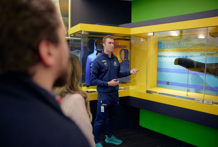 澳大利亚首都领地，堪培拉，澳大利亚运动研究所，一位澳大利亚运动研究所的运动员在向参观团介绍游泳项目 © 澳大利亚运动研究所和澳大利亚文化景点联盟版权所有