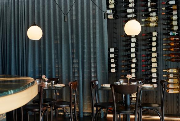 被半透明的蓝帘部分遮挡的 Pearla & Co 餐厅酒墙 © Frances Andrijich 