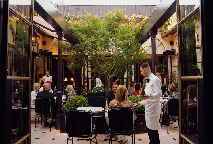 在屋顶露台 La Terrasse，一名服务生正为宾客提供服务。© Liana Hardy Photography 版权所有