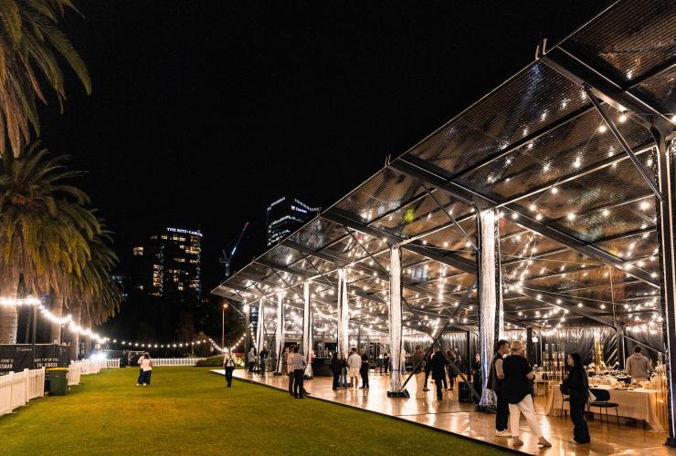 在玻璃幕墙环绕的 The Kingsman，由木质地板和草坪区构成的活动场地布置妥当，宾客云集。© The Kingsman 版权所有