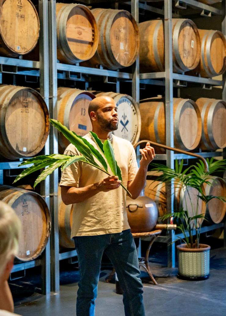 在酿酒厂里，Husk 酿酒师站在酒桶前为宾客进行讲解。© Husk 农场酿酒厂版权所有