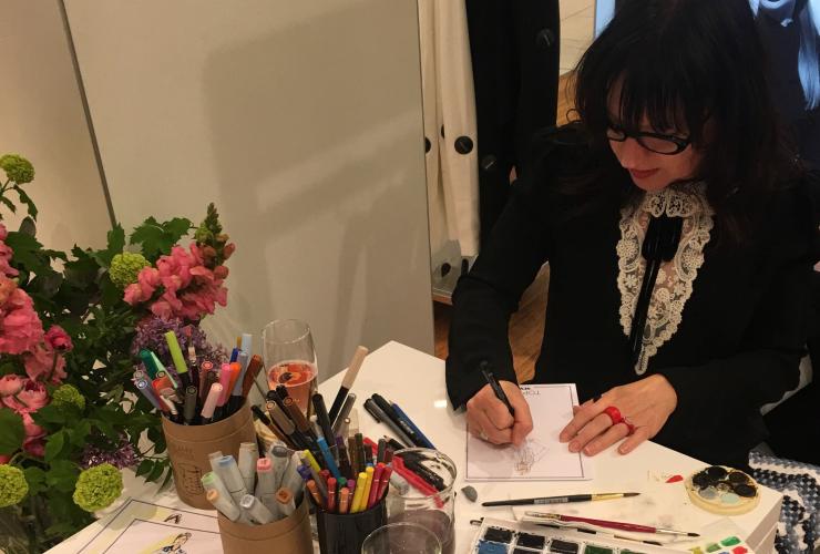艺术家 Ange Rehe 在活动现场坐在桌旁，为与会代表们现场创作肖像画 © Angie Rehe 版权所有